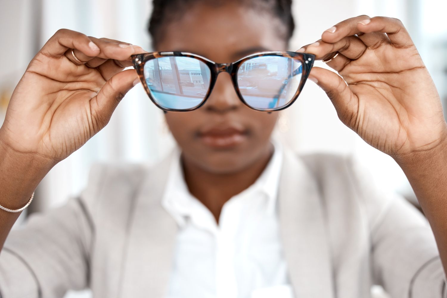 woman holding up glasses far from her face